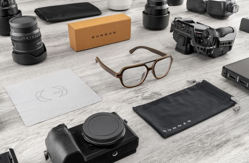 Arbor Collection Humboldt Vanity Clear Pro glasses on a table with a camera, glasses cloth and bardcboard box all next to the glasses