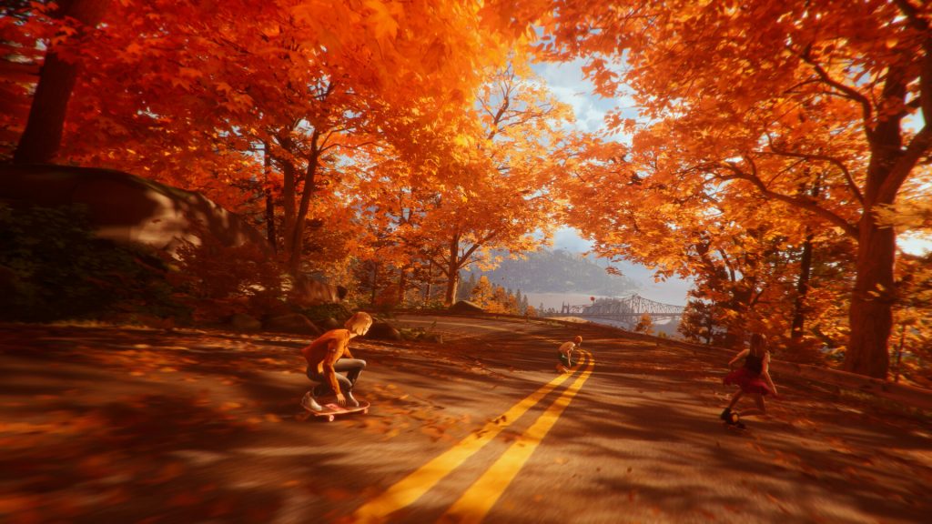 During a beautiful fall backdrop, Stacy and her friends ride their skateboards downhill.