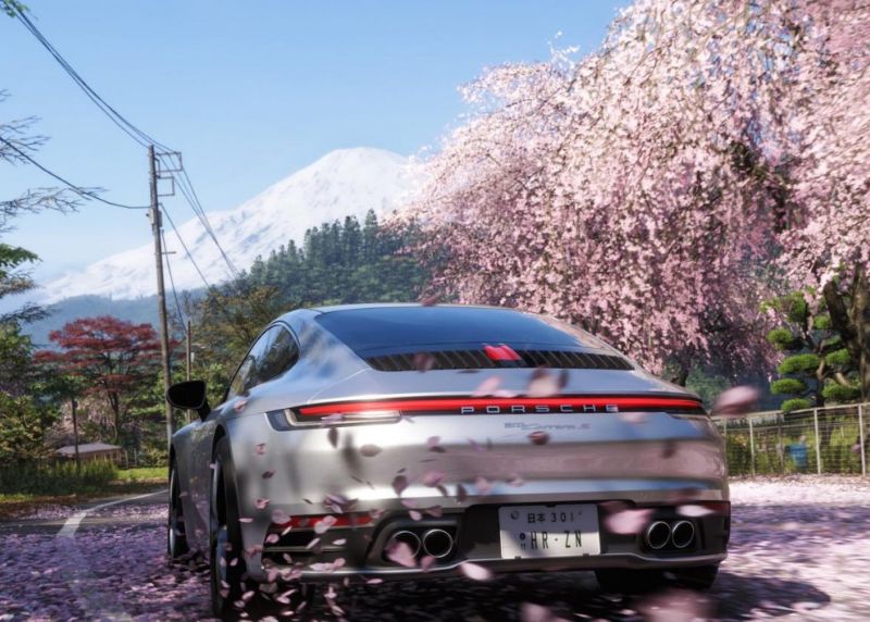 Porsche driving on a cherry blossoms petal covered road